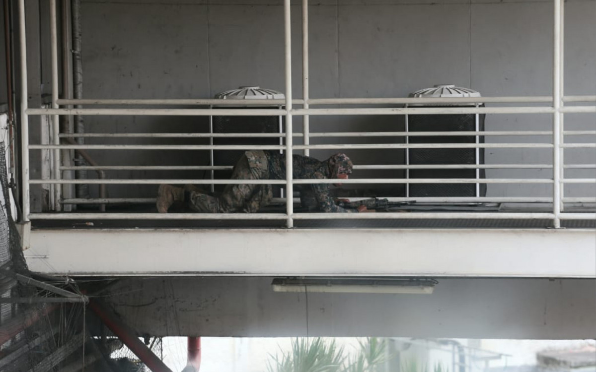 Um dos policiais tentando se aproximar do local do ônibus sequestrado na tarde desta terça-feira (12)
