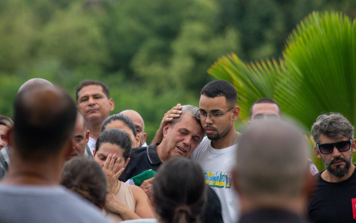 Carlos Henrique Fernandes, pai do sargento da PM Gabriel Fernandes, é consolado pelo filho caçula - Renan Areias / Agência O Dia