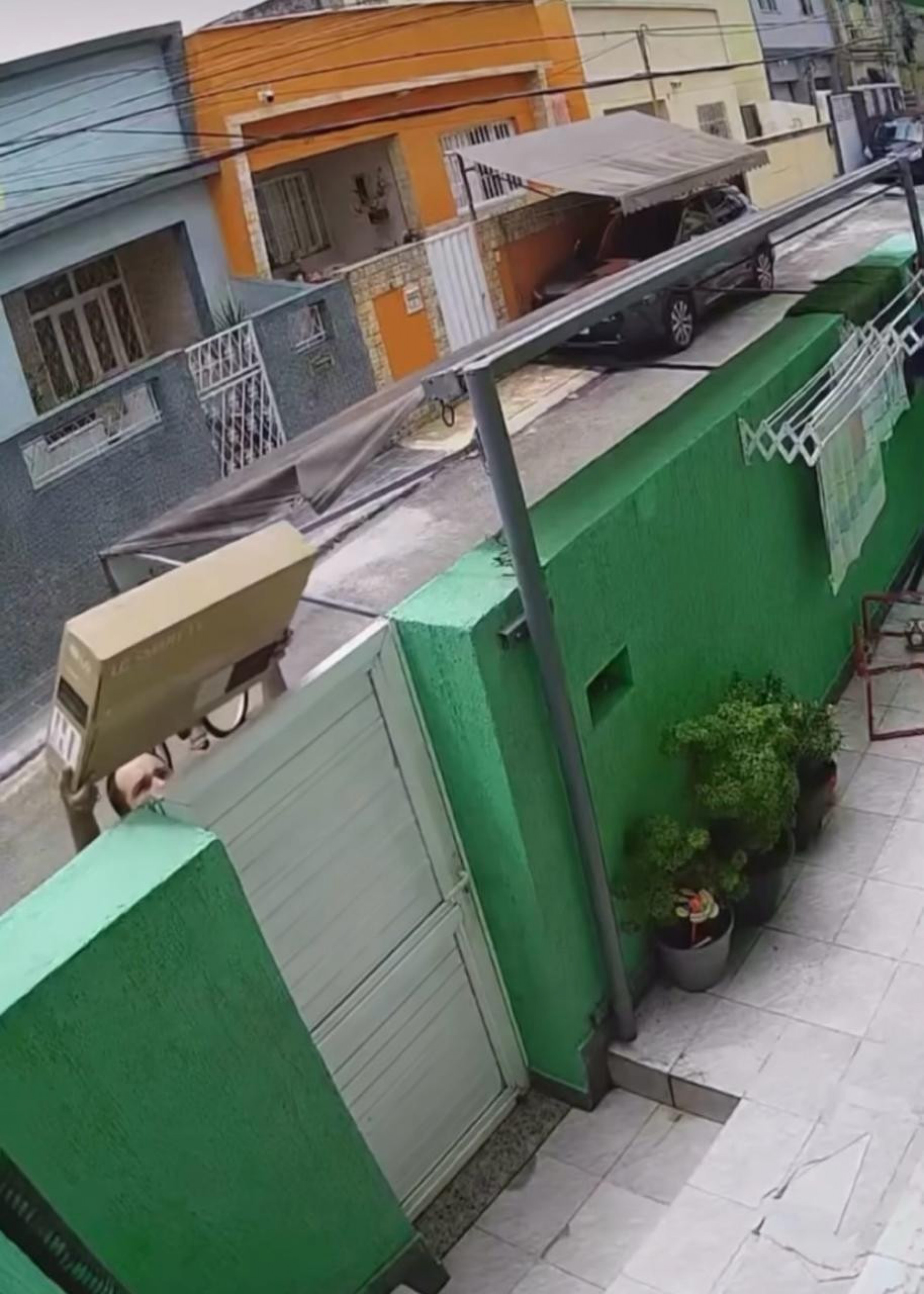 Entregador arremessa televisão por cima de portão e danifica aparelho