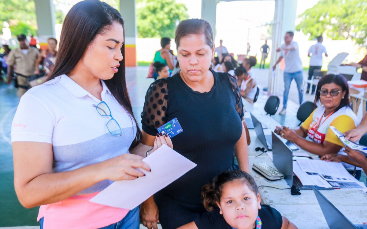 A secretária Clarice Santos conversa com Caroline Alessandra da Costa, que estava com a filha Lara Viana, e recebeu o cartão