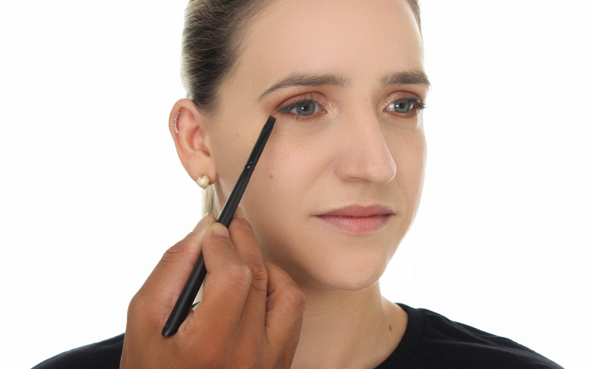 Com  o pincel chanfrado, esfume a sombra na cor marrom na parte inferior dos olhos