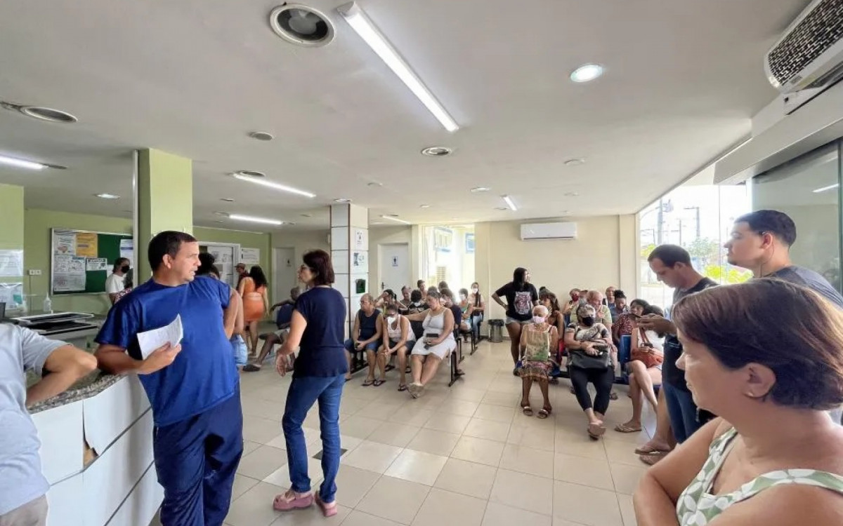 Os assentos todos ocupados, pacientes em pé do lado externo do Pronto Socorro