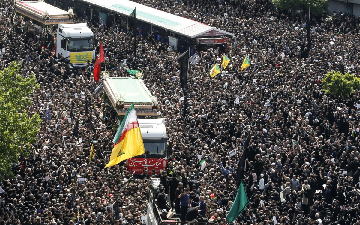 Pessoas em luto seguram cartazes do presidente iraniano, Ebrahim Raisi