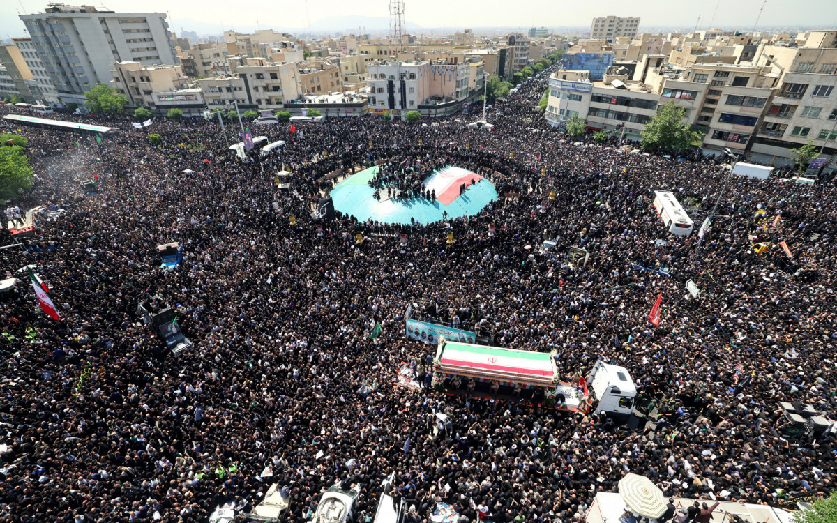 Pessoas em luto seguram cartazes do presidente iraniano, Ebrahim Raisi