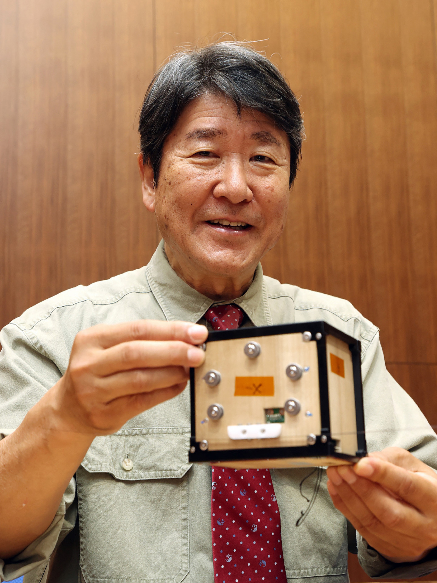 Takao Doi com o satélite de madeira  - STR / JIJI Press / AFP