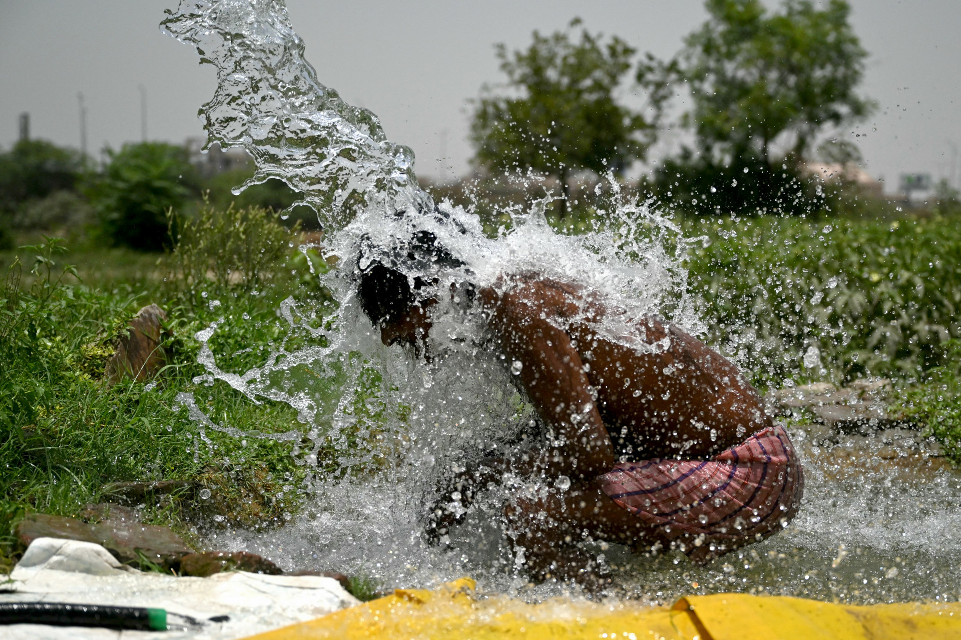 Garoto tenta se refrestar em dia recorde de temperatura na capital da Índia - Arun Sankar / AFP