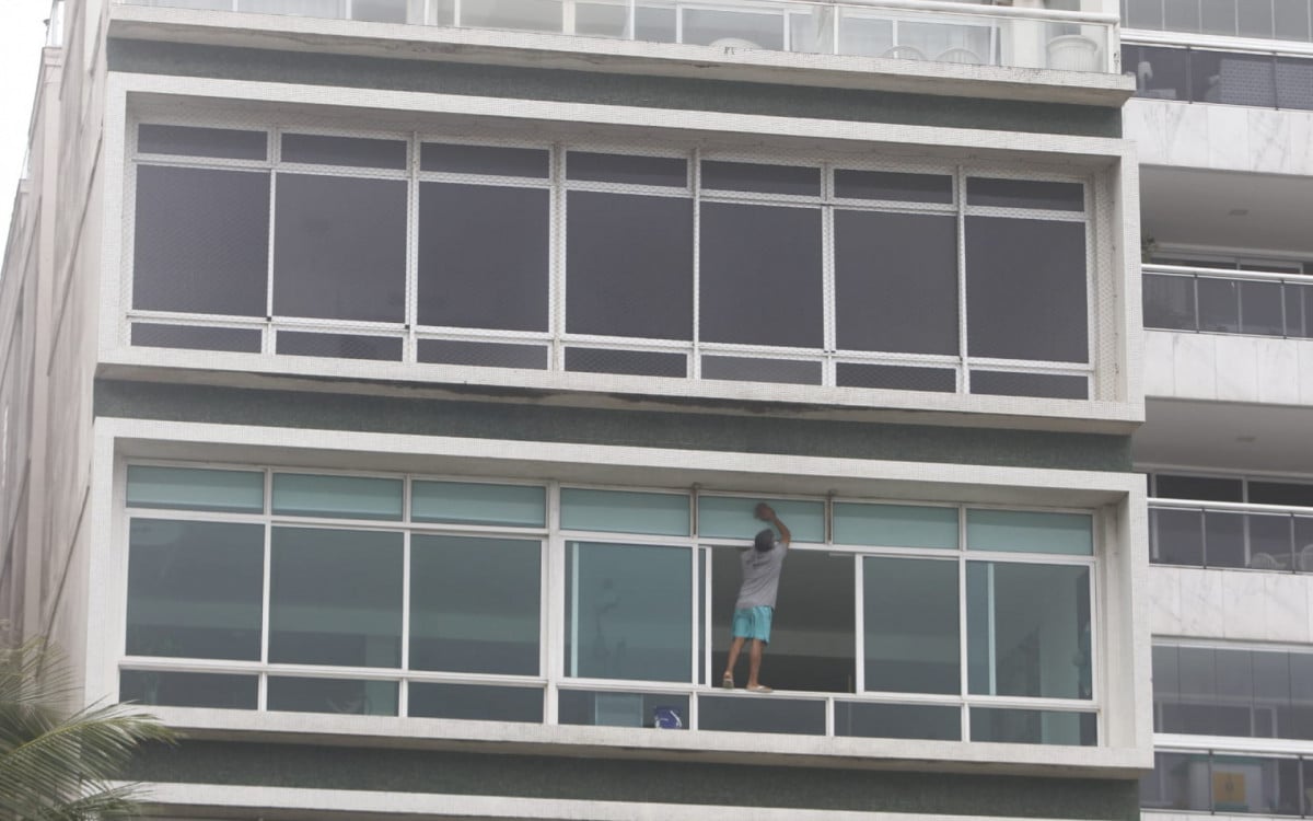 Homem limpa janela no quarto andar de prédio sem qualquer equipamento de segurança - Reginaldo Pimenta