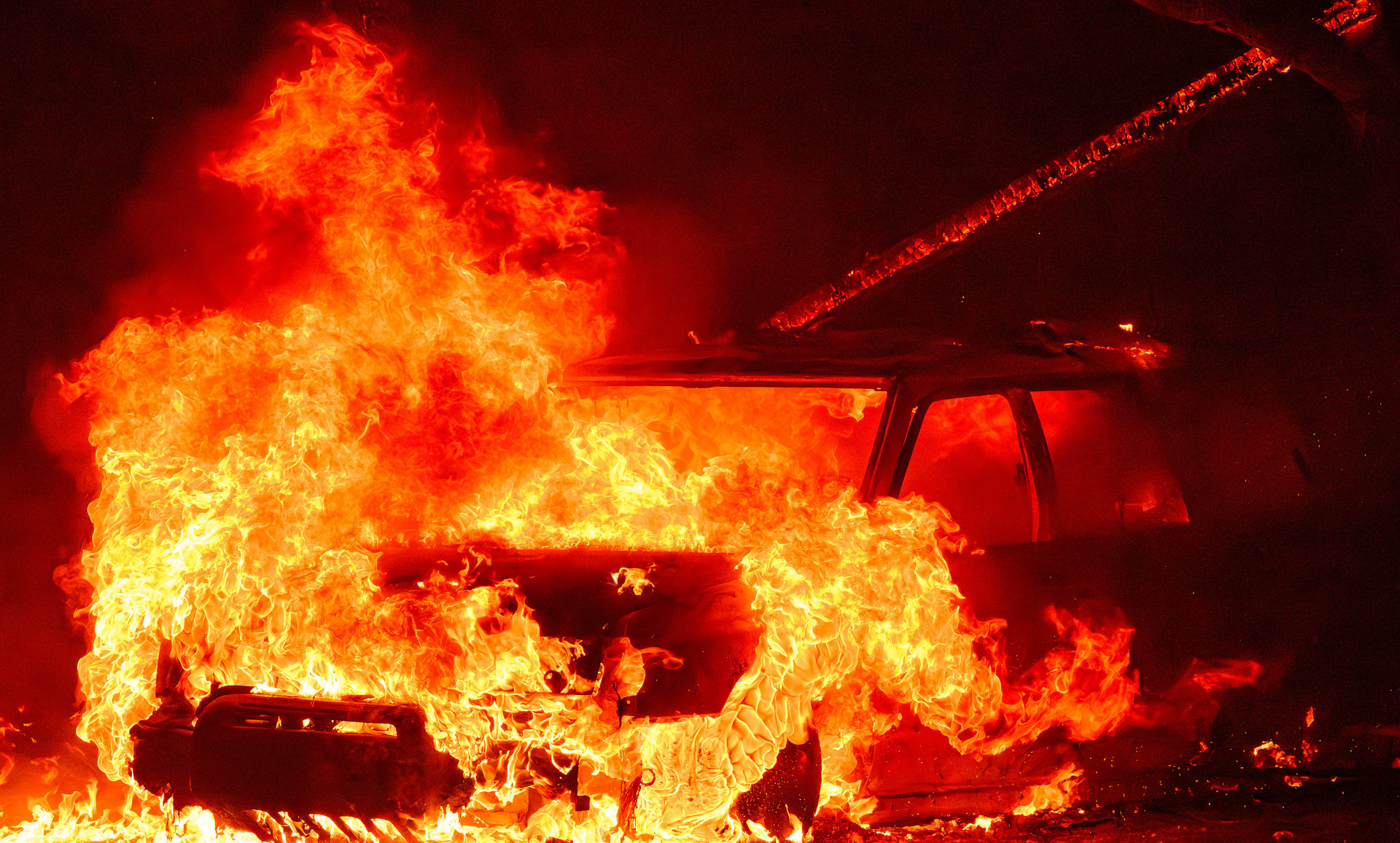 Um suspeito foi preso por iniciar as chamas ao empurrar um carro em chamas em um barranco - Josh Eldeson / AFP