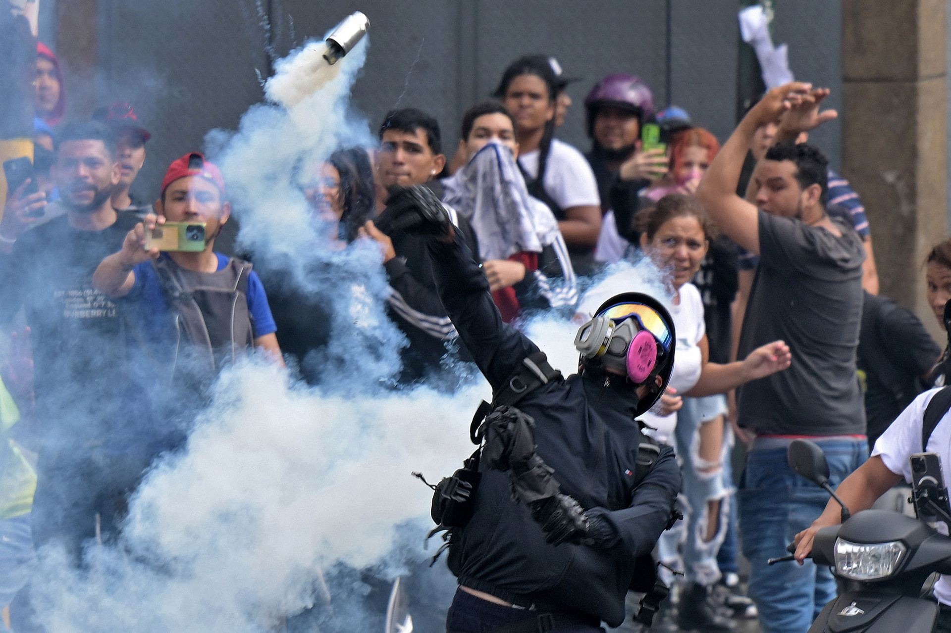 Manifestante mascarado lança bomba de gás - Yuri Cortez/AFP