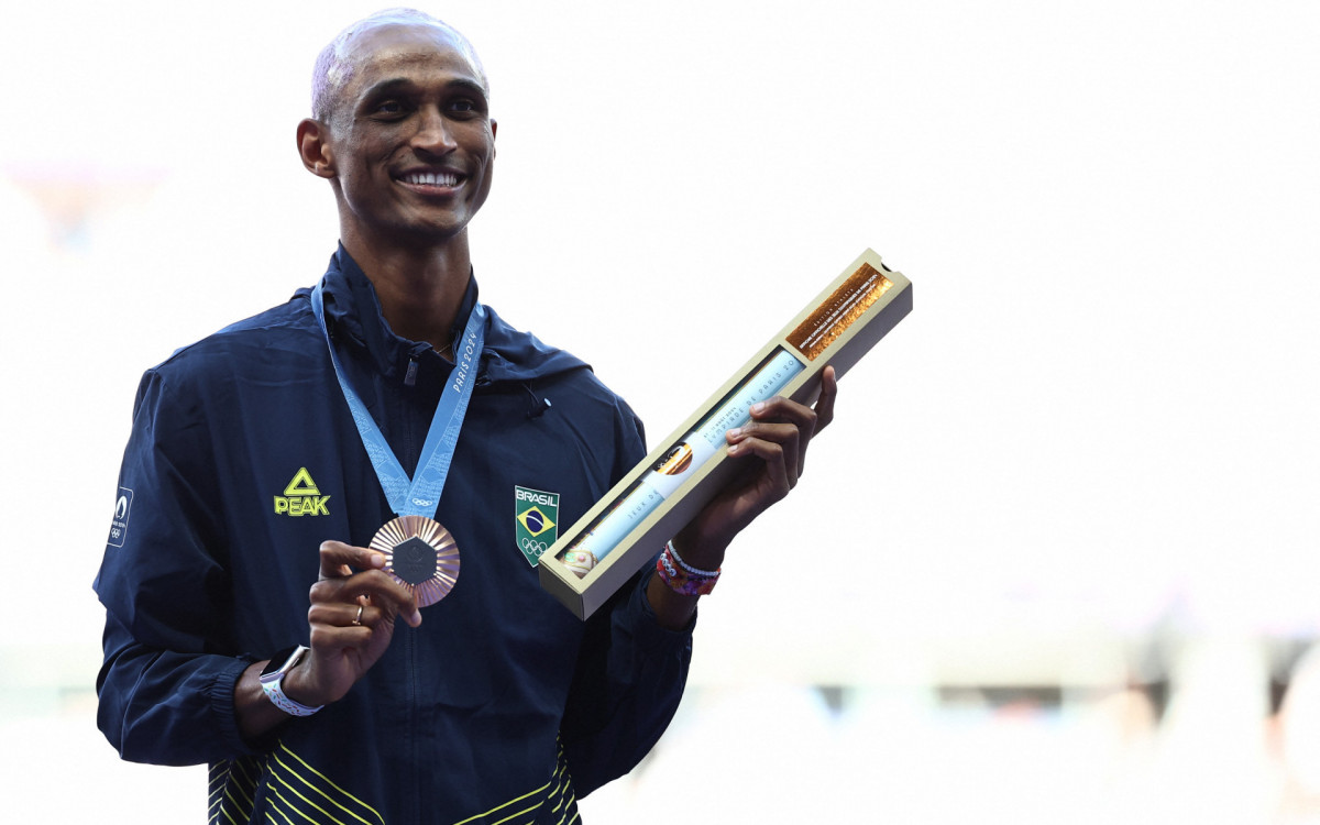 Bronze medallist Brazil\'s Alison Dos Santos celebrates on the podium during the victory ceremony for the men\'s 400m hurdles athletics event during the Paris 2024 Olympic Games at Stade de France in Saint-Denis, north of Paris, on August 10, 2024.
Anne-Christine POUJOULAT / AFP