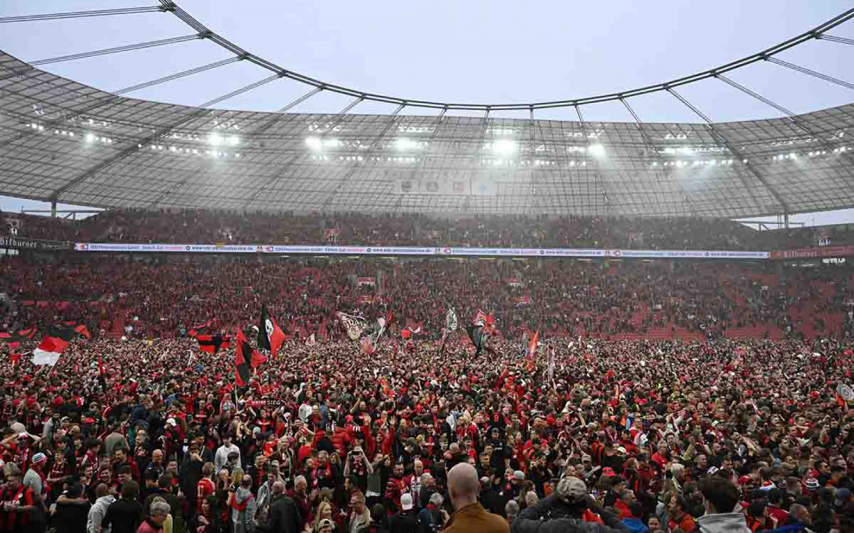 Leverkusen fans celebrate on the pitch after the German first division Bundesliga football match Bayer 04 Leverkusen v Werder Bremen in Leverkusen, western Germany, on April 14, 2024. Bayer Leverkusen were crowned 2023-24 Bundesliga champions for the first time on April 14, 2024.  (Photo by INA FASSBENDER / AFP) / DFL REGULATIONS PROHIBIT ANY USE OF PHOTOGRAPHS AS IMAGE SEQUENCES AND/OR QUASI-VIDEO (Photo by INA FASSBENDER/AFP via Getty Images)