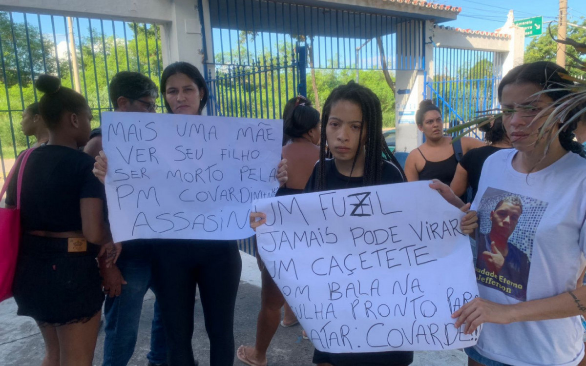 Familiares de Jefferson de Araújo Costa com cartazes no enterro do jovem