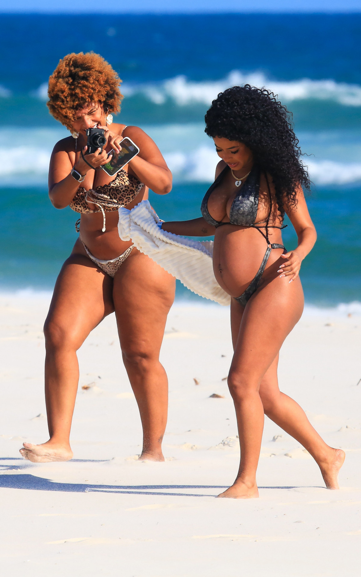 Lorena Maria faz ensaio de fotos e exibe barrigão de grávida em praia no Rio ao lado de amiga 