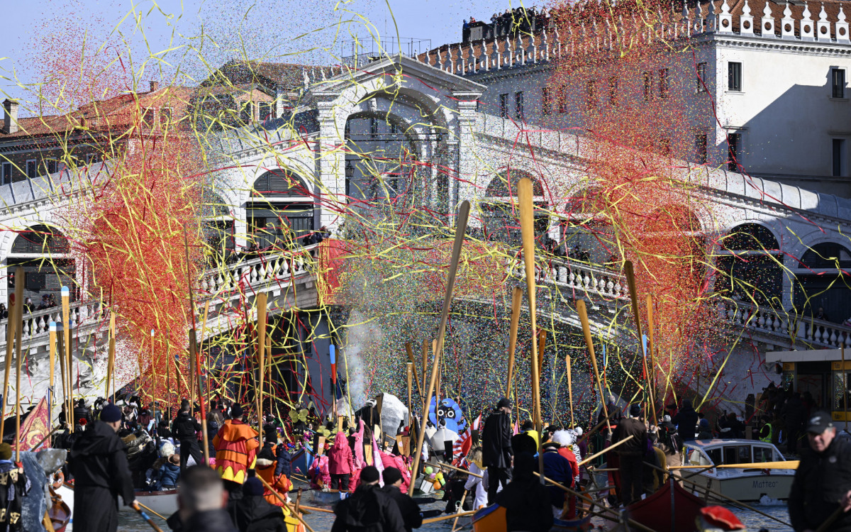 Confetes explodem enquanto barcos decorados navegam no Grande Canal