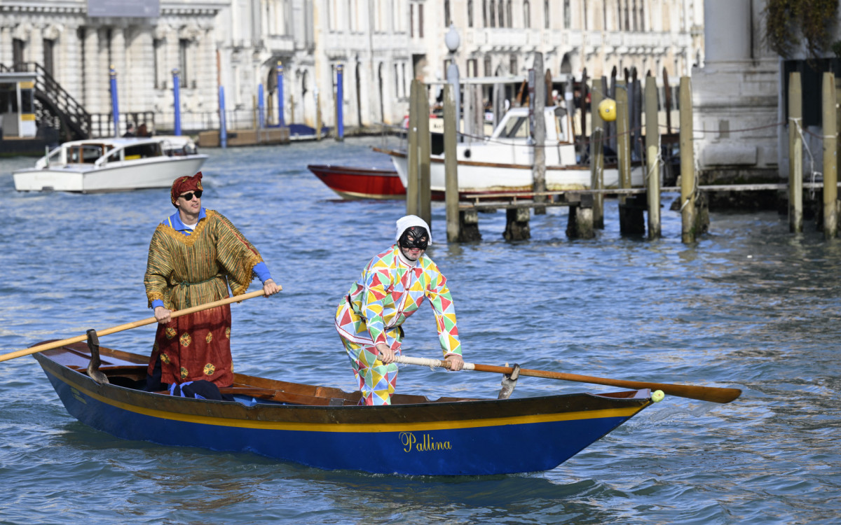 Homem vestido como Arlequim rema durante um desfile no Grande Canal no Carnaval de Veneza