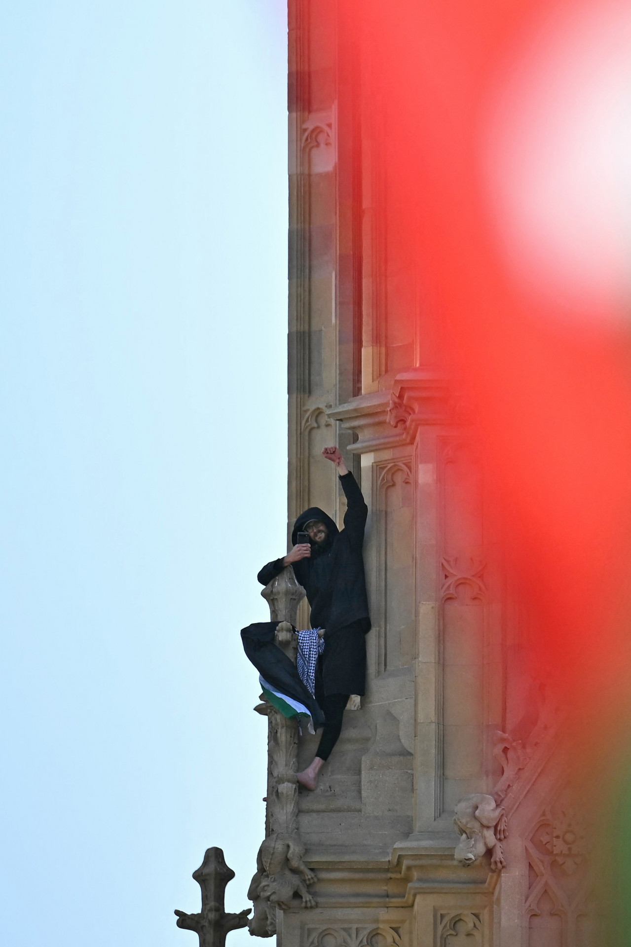 Homem subiu vários metros na Elizabeth Tower e ficou descalço em uma saliência segurando a bandeira - AFP