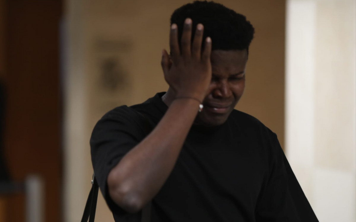 Irm&atilde;o mais velho de Mo&iuml;se se emociona do lado de fora da sala onde acontece o j&uacute;ri popular