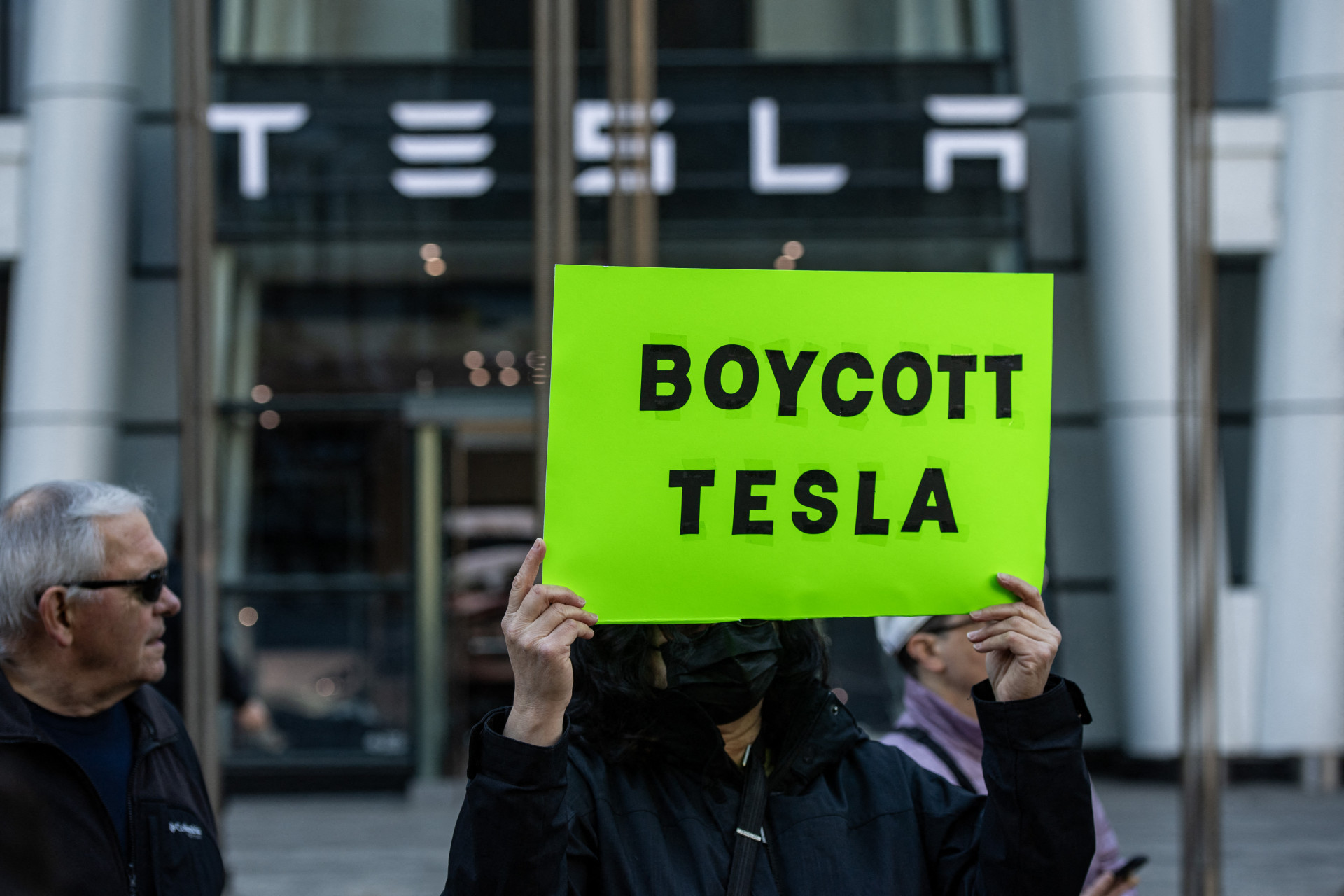 Manifestantes seguram cartazes e cantam cânticos durante um protesto contra Elon Musk - AFP