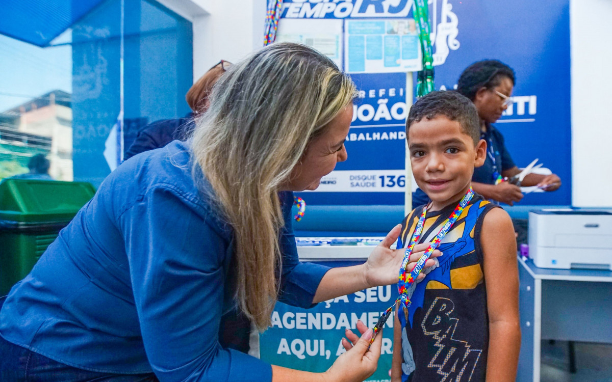 A coordenadora do CER, Viviane Alves Costa entregando a cordinha de identificação de crianças com Transtorno do Espectro Autista (TEA)