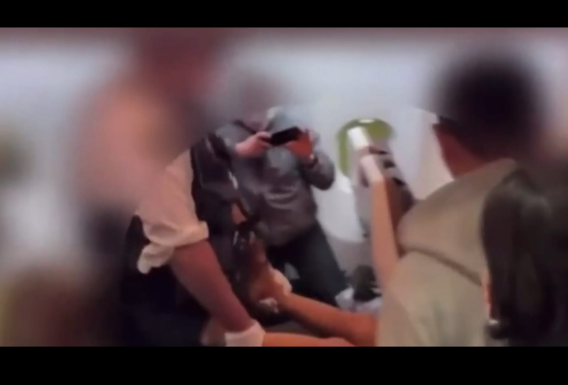 Homem sendo carregado por agentes após morder tripulante em avião no Japão