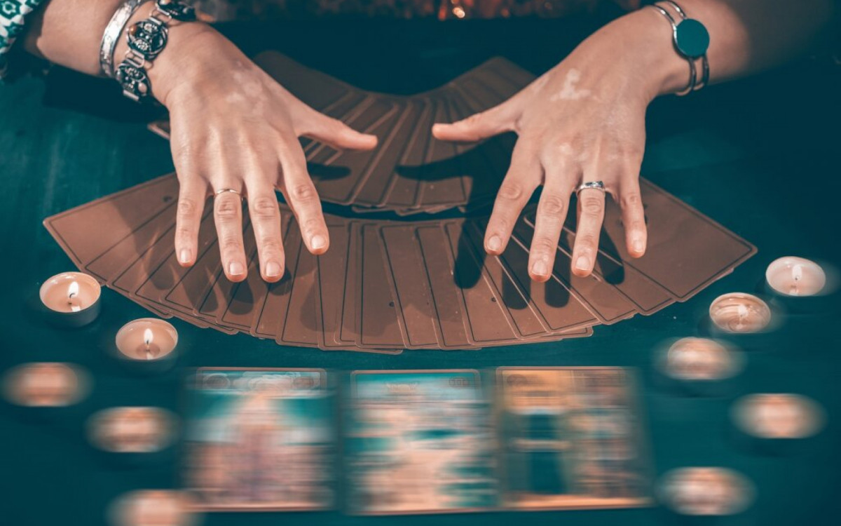 Fortune teller with tarot cards on table near burning candles.Tarot cards spread on table with crystal ball.Forecasting concept.