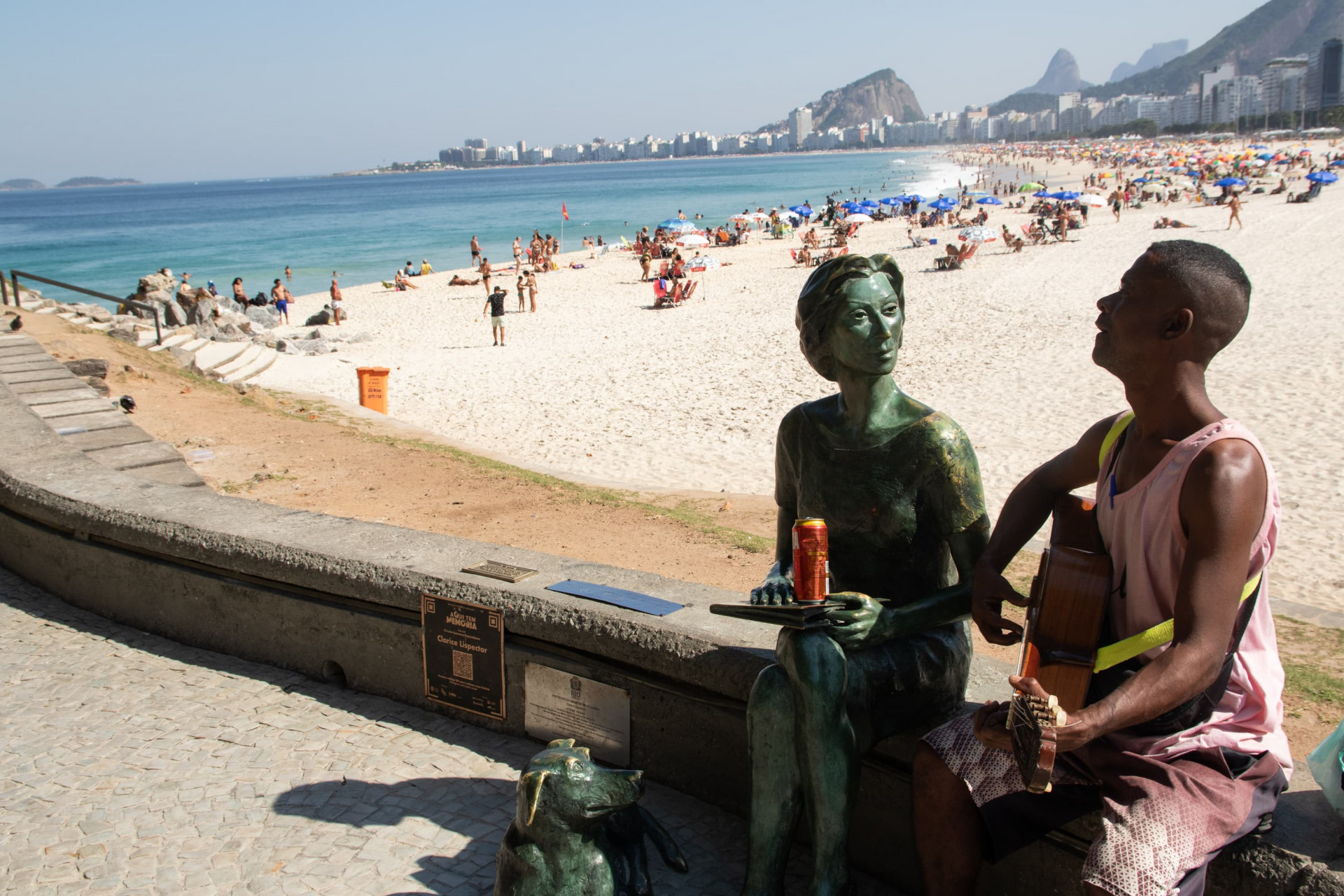 Carioca toca violão ao lado da estátua da Clarice Lispector, na Praia do Leme - Érica Martin / Agência O Dia