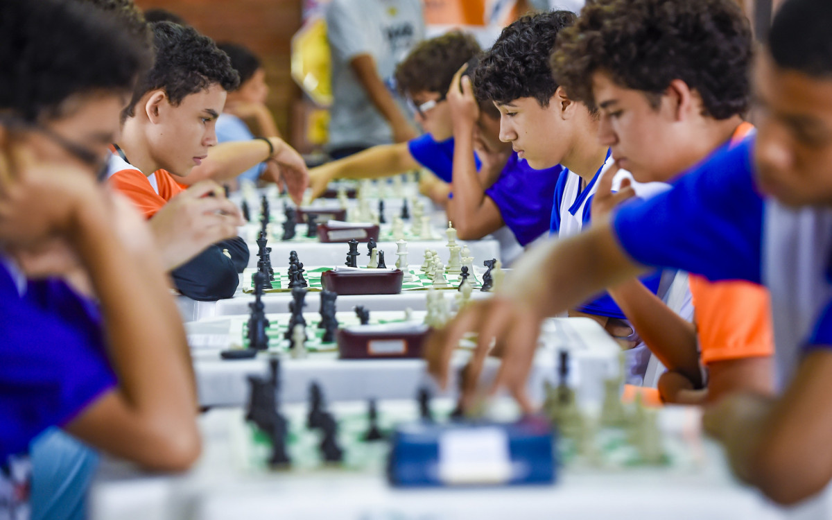 Jovens atletas mostram estratégia no xadrez durante os Jogos.
