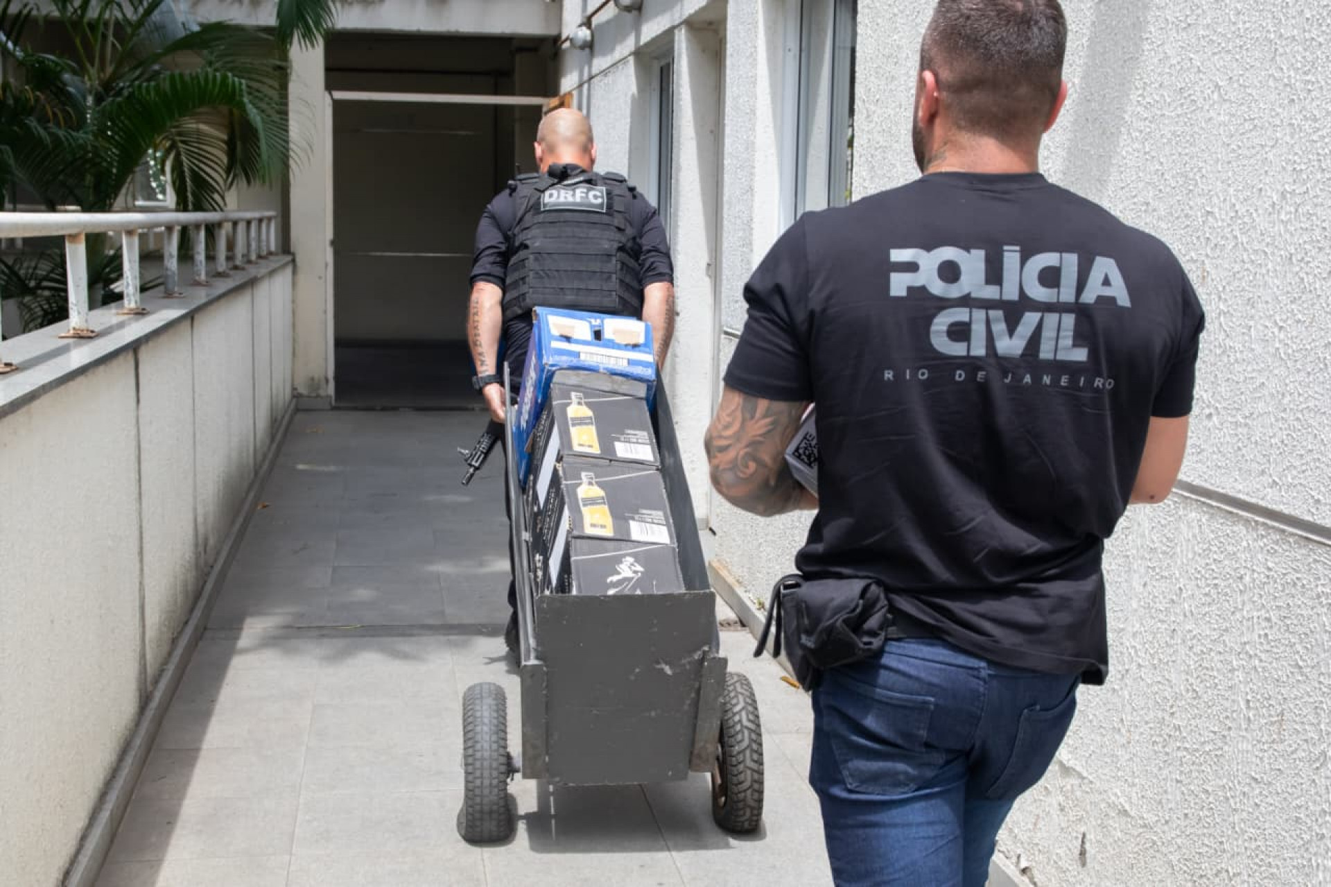 Agentes levando bebidas apreendidas, que serão encaminhadas para análise - Érica Martin / Agência O Dia