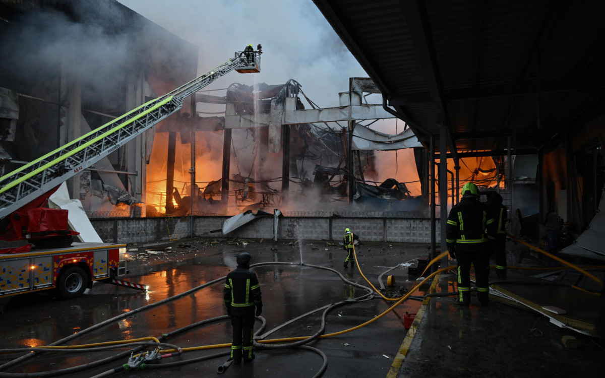 Bombeiros ucranianos apagam um incêndio em um depósito de alimentos após um ataque de míssil russo em Kiev - AFP