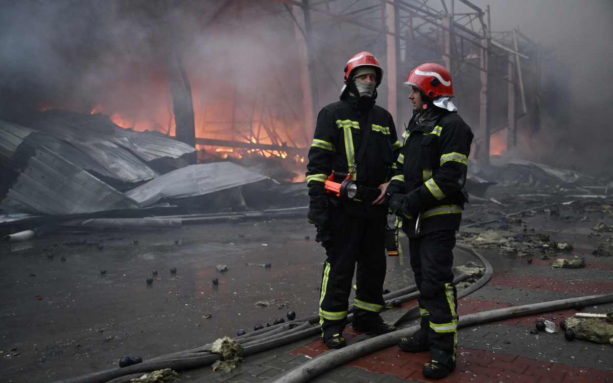 Bombeiros ucranianos apagam um incêndio em um depósito de alimentos após um ataque de míssil russo em Kiev - AFP