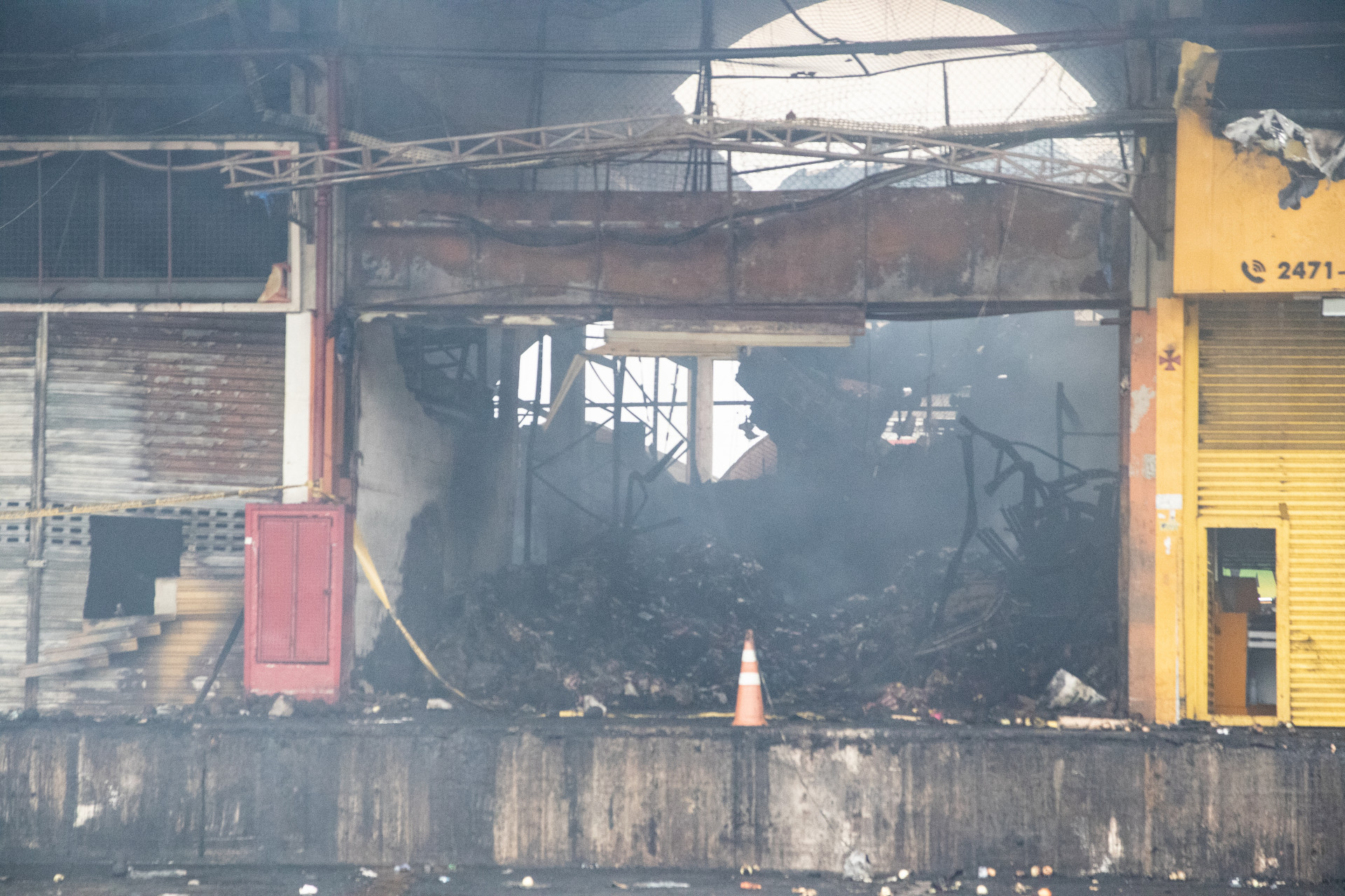 Foco de fumaça sob os escombros em uma das lojas que pegou fogo no Ceasa de Irajá, nesta terça-feira (9) - Érica Martin/Agência O Dia