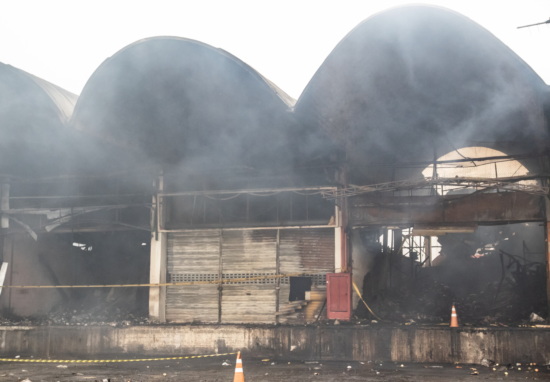 Foco de fumaça sob os escombros em uma das lojas que pegou fogo no Ceasa de Irajá, nesta terça-feira (9) - Érica Martin/Agência O Dia