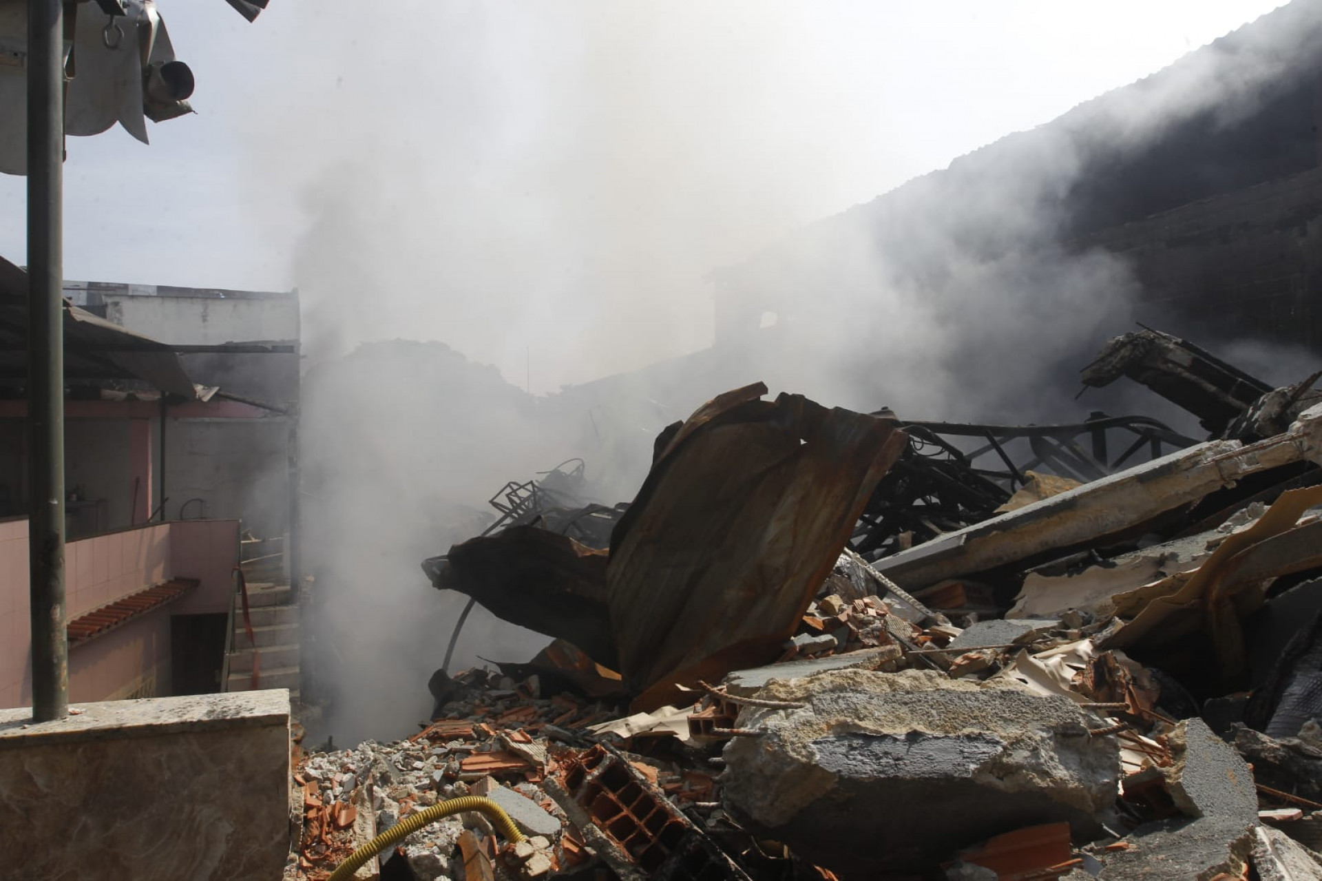 Fogo em meio aos escombros seguem produzindo fumaça no terreno, em Ramos - Reginaldo Pimenta / Agência O Dia