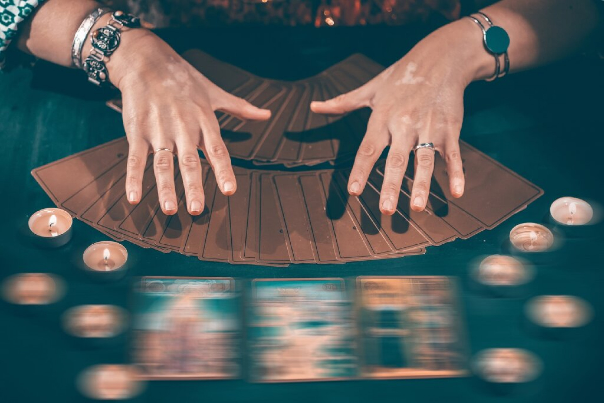 Fortune teller with tarot cards on table near burning candles.Tarot cards spread on table with crystal ball.Forecasting concept.