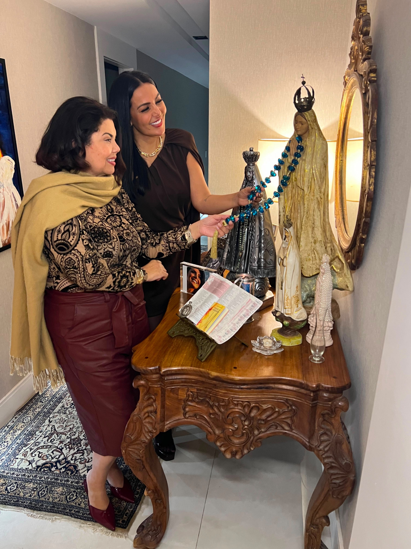 Fabiana Karla e Gardênia Cavalcanti observam as imagens religiosas que pertenceram a Hebe Camargo