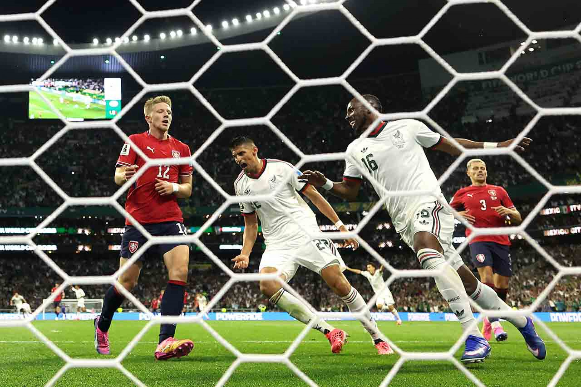 MEXICO CITY, MEXICO - JUNE 24: (EDITOR'S NOTE: Image was captured using a remote camera from behind the goal.) Guillermo Martinez #22 and Julian Quinones #16 of Mexico celebrate the team's first goal scored by Mateo Chavez #20 (not pictured) during the FIFA World Cup 2026 Group A match between Czechia and Mexico at Mexico City Stadium on June 24, 2026 in Mexico City, Mexico. (Photo by Lars Baron/Getty Images)