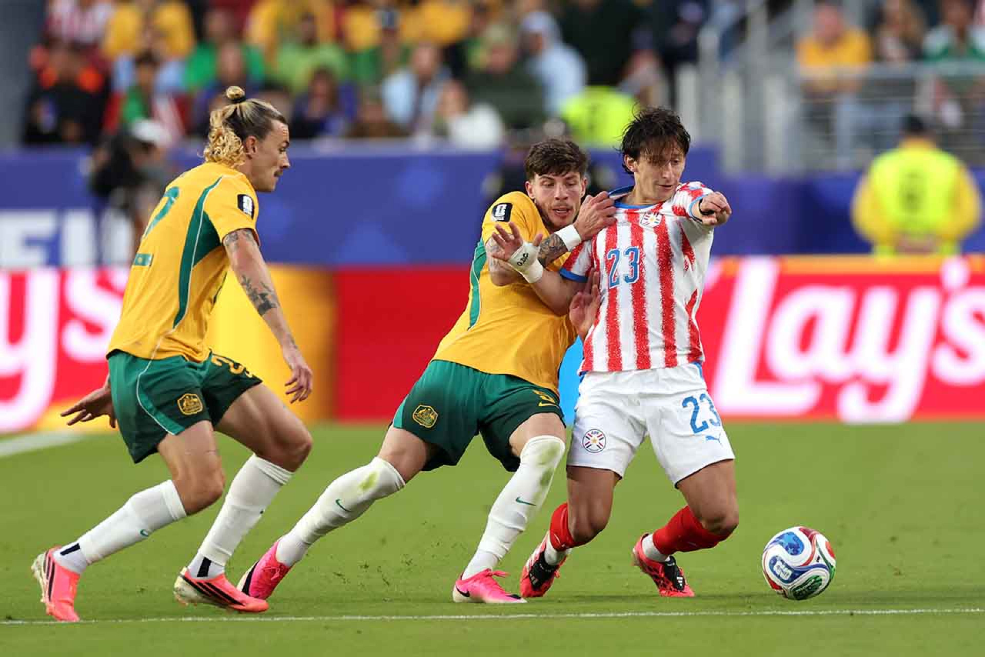 SANTA CLARA, CALIFORNIA - JUNE 25: Matias Galarza #23 of Paraguay competes for the ball against Jackson Irvine #22 and Jordan Bos #5 of Australia during the FIFA World Cup 2026 Group D match between Paraguay and Australia at San Francisco Bay Area Stadium on June 25, 2026 in Santa Clara, California. (Photo by Stu Forster/Getty Images)