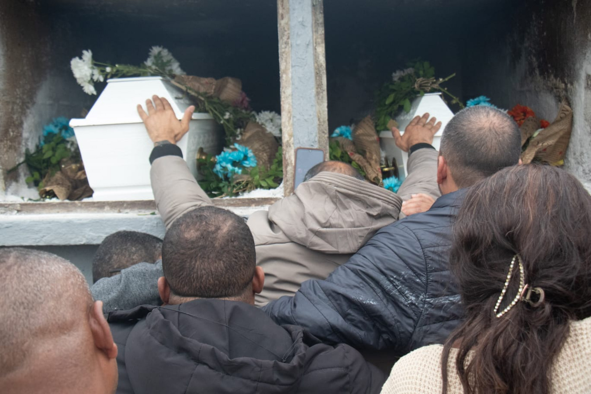 Pai das meninas acariciou os caix&otilde;es durante a despedida das filhas - &Eacute;rica Martin / Ag&ecirc;ncia O Dia