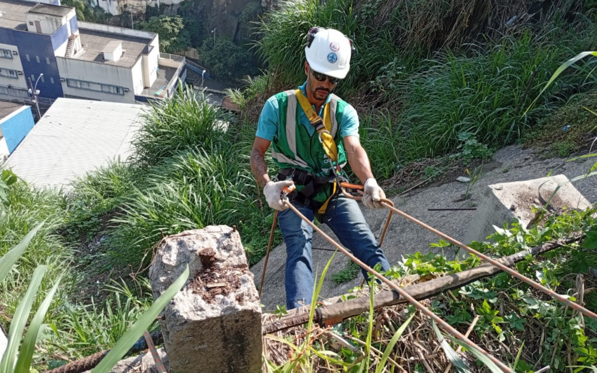 Com o uso de t&eacute;cnicas de rapel, profissional da &Aacute;guas do Rio trabalha suspenso em encosta do Morro da Provid&ecirc;ncia para instalar tubula&ccedil;&otilde;es de saneamento onde m&aacute;quinas convencionais n&atilde;o chegam - Divulga&ccedil;&atilde;o/&Aacute;guas do Rio