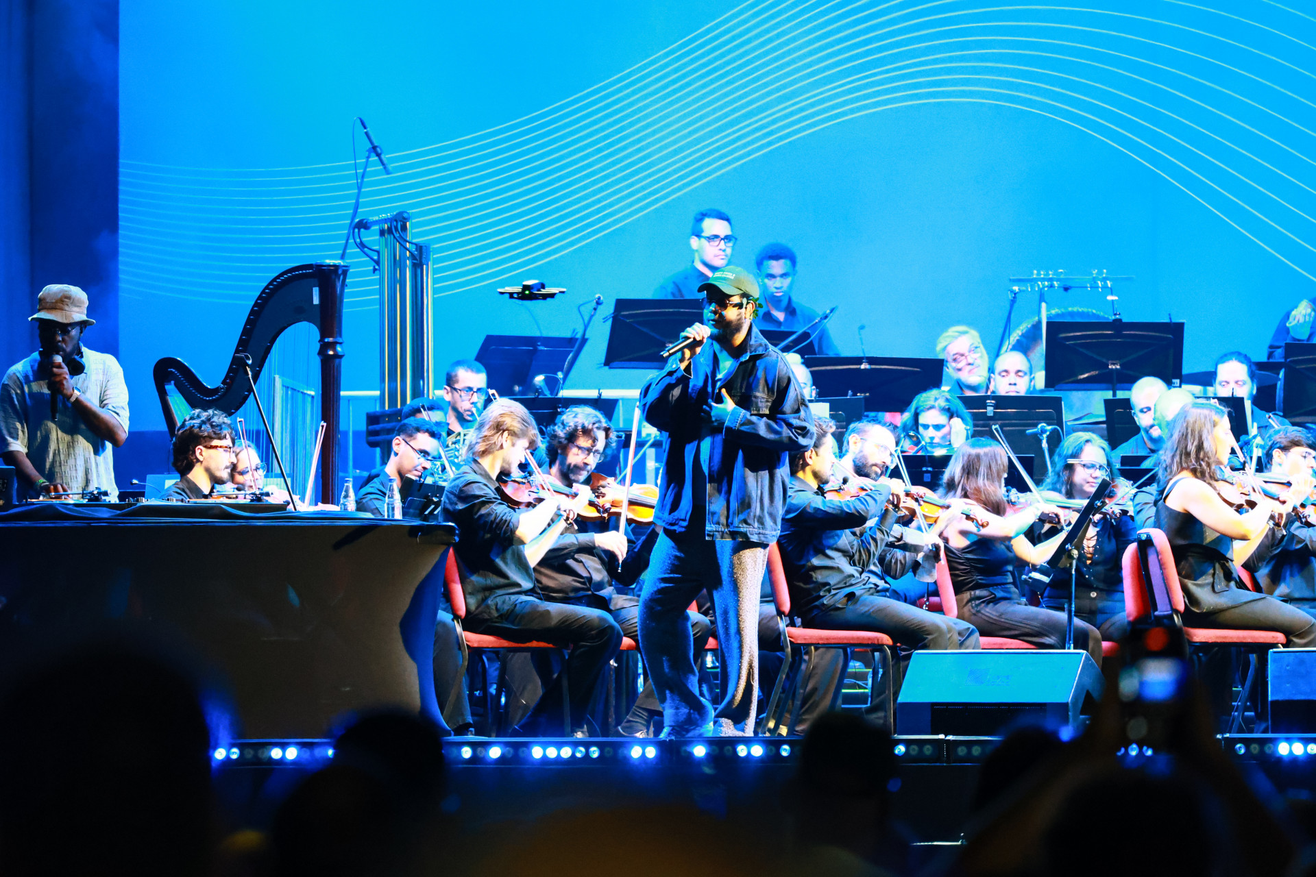 O Projeto Aquarius reuniu Leci Brandão, Emicida e a Orquestra Sinfônica Brasileira (OSB) na Praça Mauá, na Zona Portuária, neste sábado (19). Sob a regência do maestro Carlos Prazeres, o show gratuito faz parte da programação oficial da Semana de Arte do Rio, que se estende até o dia 27 de setembro.   - Neemias Gonzaga/Parceiro/ Agência O Dia