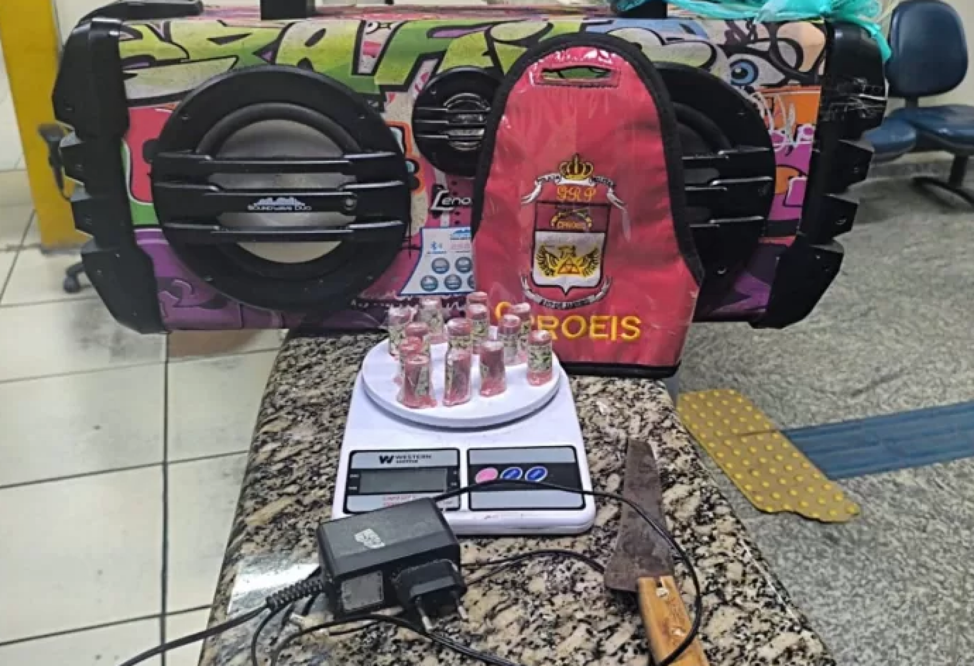 13 trouxinhas de maconha, uma balança de precisão, uma faca, uma caixa de som e um carregador 